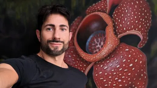 man in black tshirt stands in front f a paiting of a flower