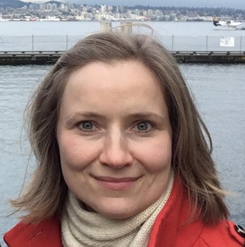 woman with shoulde length fair hair in a red coat. head and shoulders only